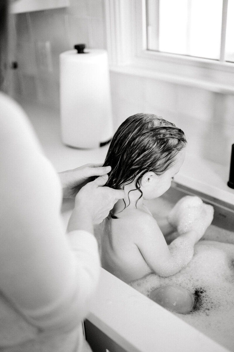 Black and white photo of little girl getting her hair washed