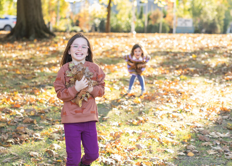 Siblings playing in fall leaves at a Union County, NJ park.