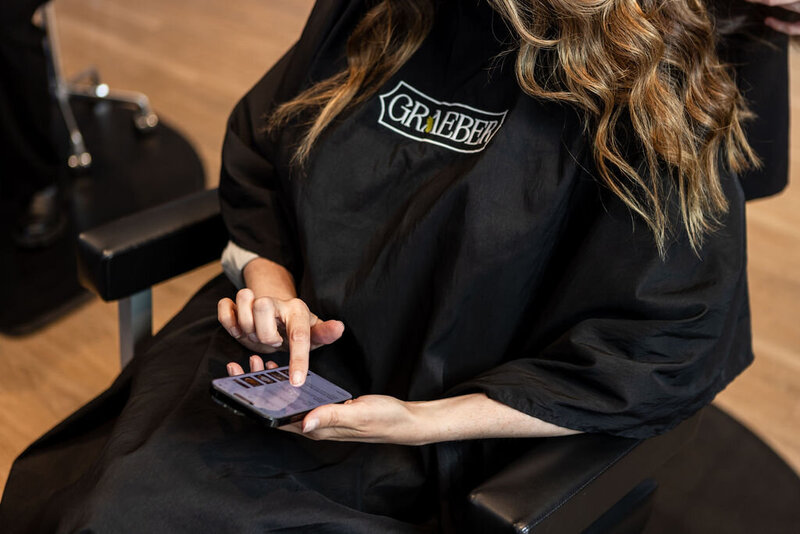 Woman sitting in salon chair on her phone