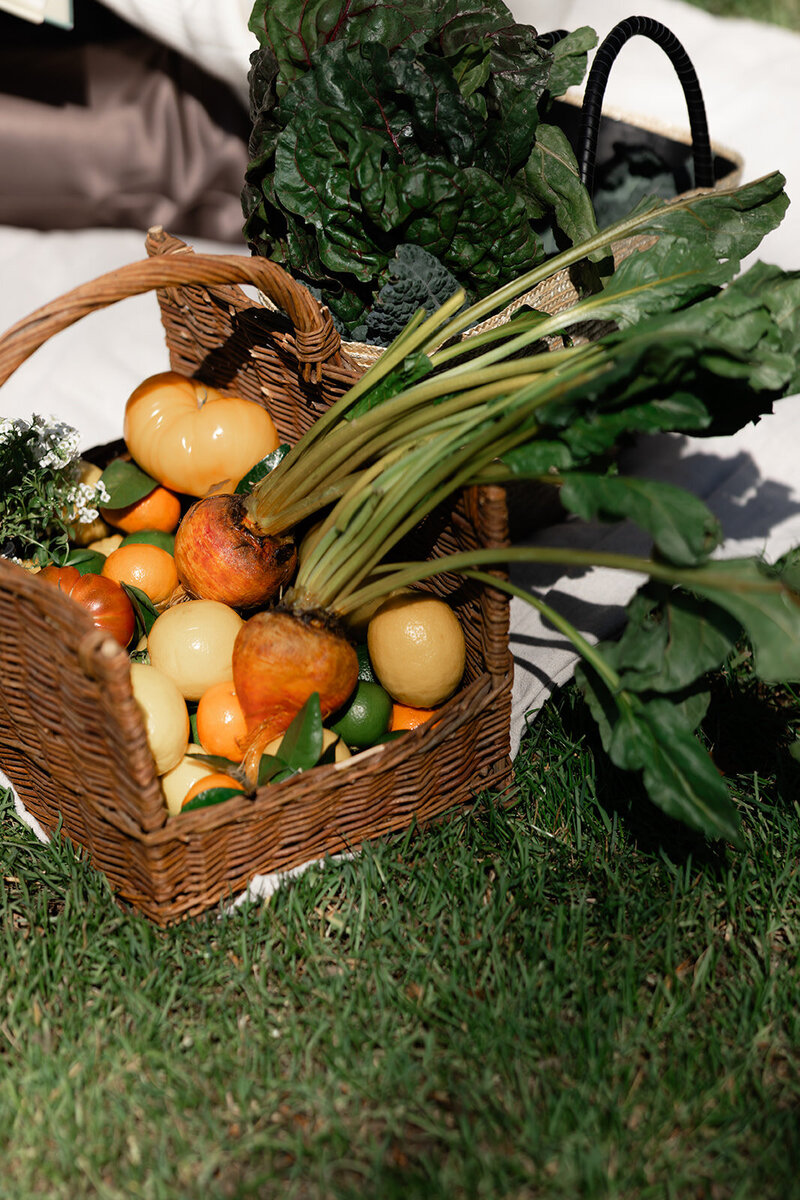 Fresh seasonal vegetables in a wicker basket outside, representing nourishing, whole-food living