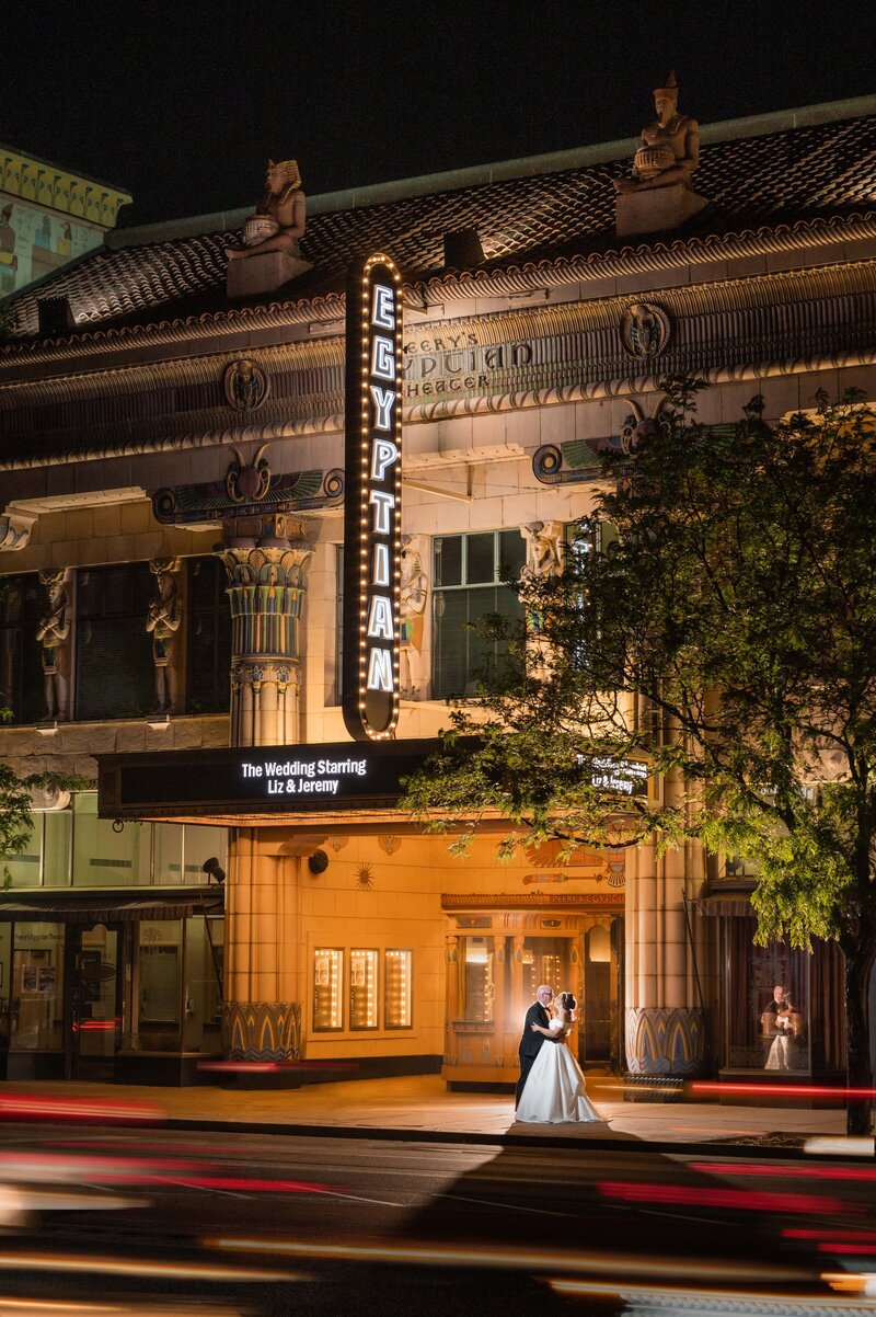 Bride and groom share a kiss at night outside of the Egyptian Theater where they were married. Their names are on the marquee.