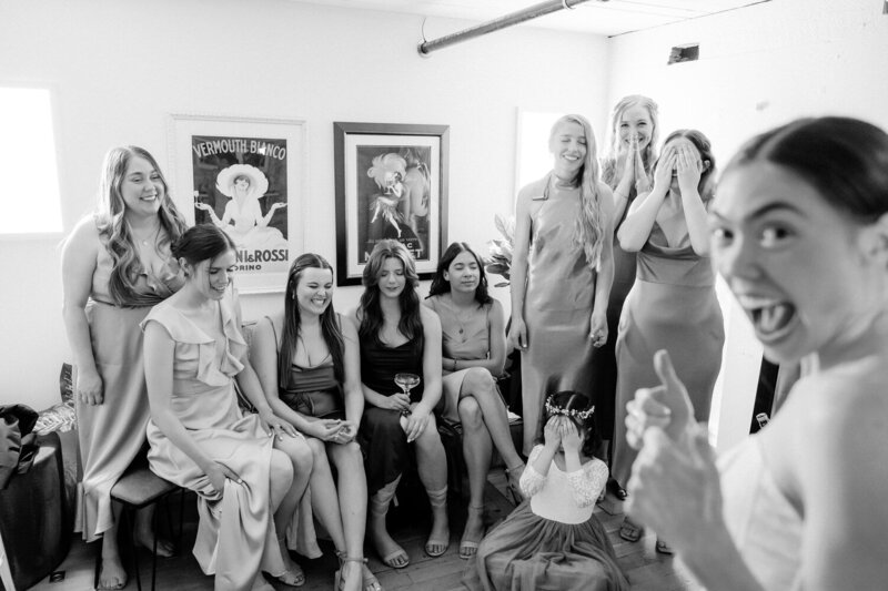 Bride gives a thumbs up to the camera before doing a first look with her bridesmaids