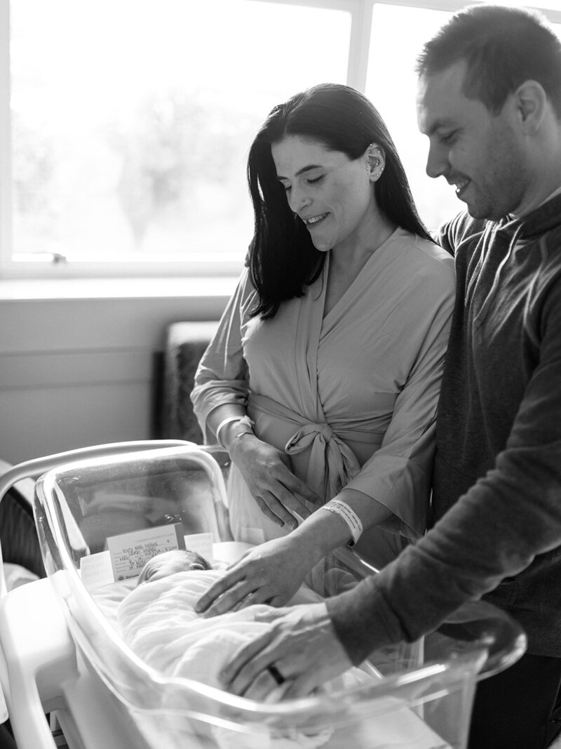 New parents looking down at baby in hospital crib