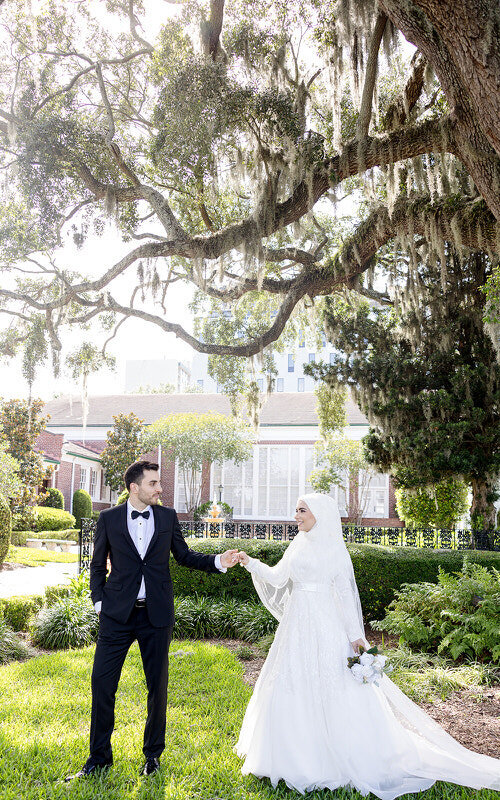 Classic Arabic American wedding photo of a couple walking among mossy oaks in St Augustine 