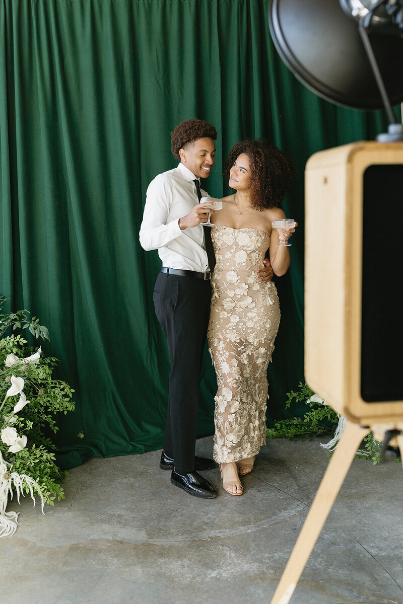 Engaged couple using a print photo booth with a luxury wedding backdrop and florals at an Ottawa wedding.