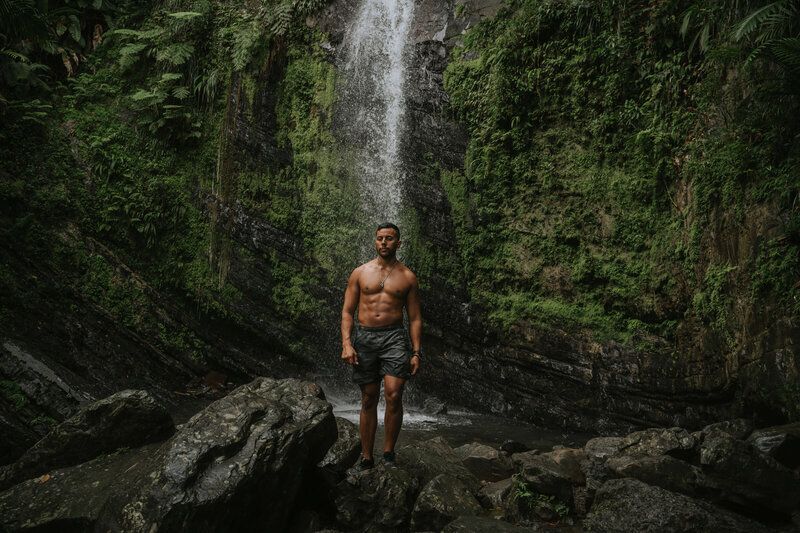 Man standing in front of a waterfall in the tropics