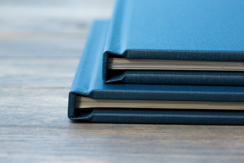 Two blue photo albums stacked on a wood table.
