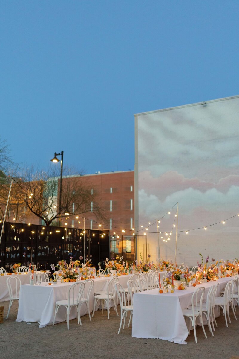 Empty outdoor wedding reception tables with twinkle lights.