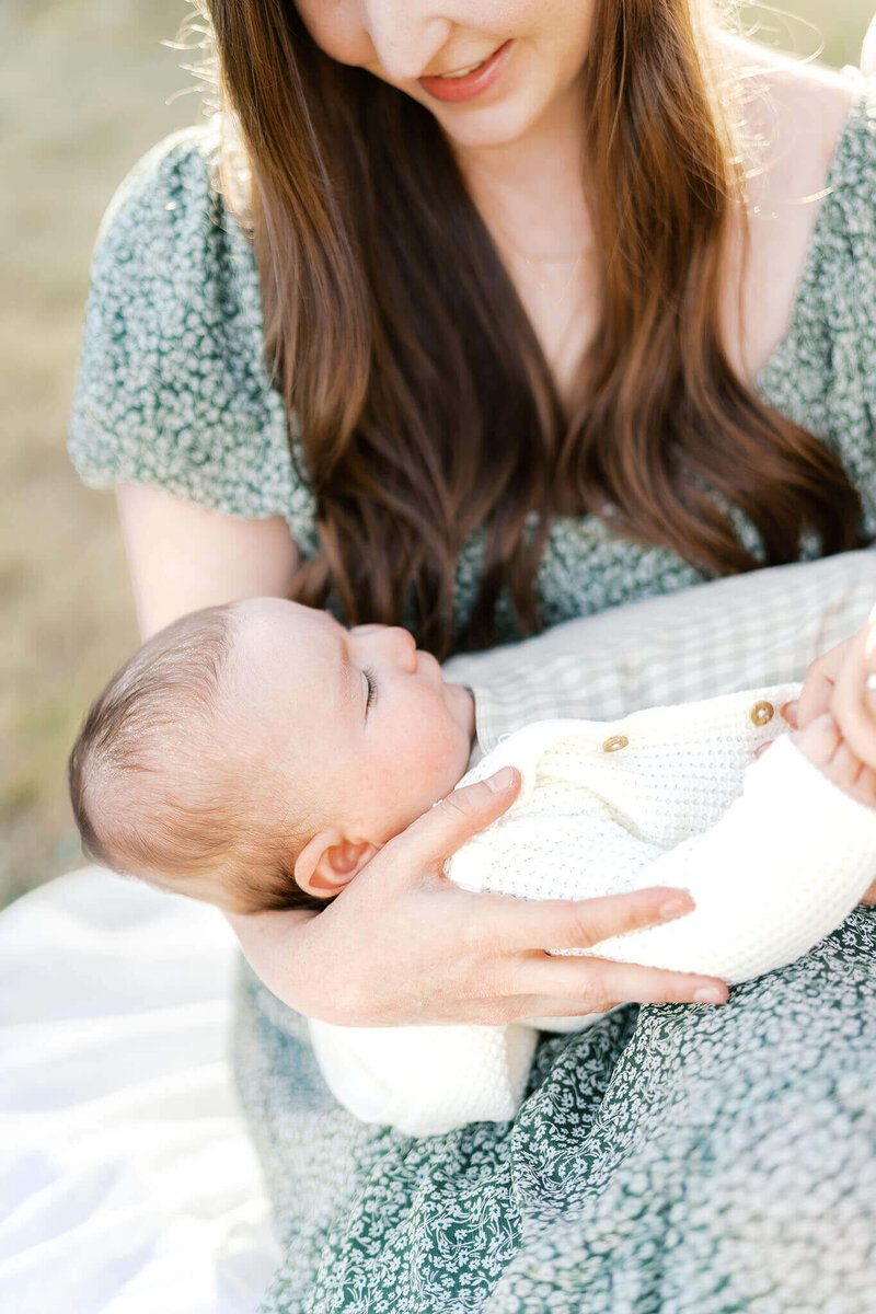 detail of candid moment while mom holds baby during outdoor newborn photos