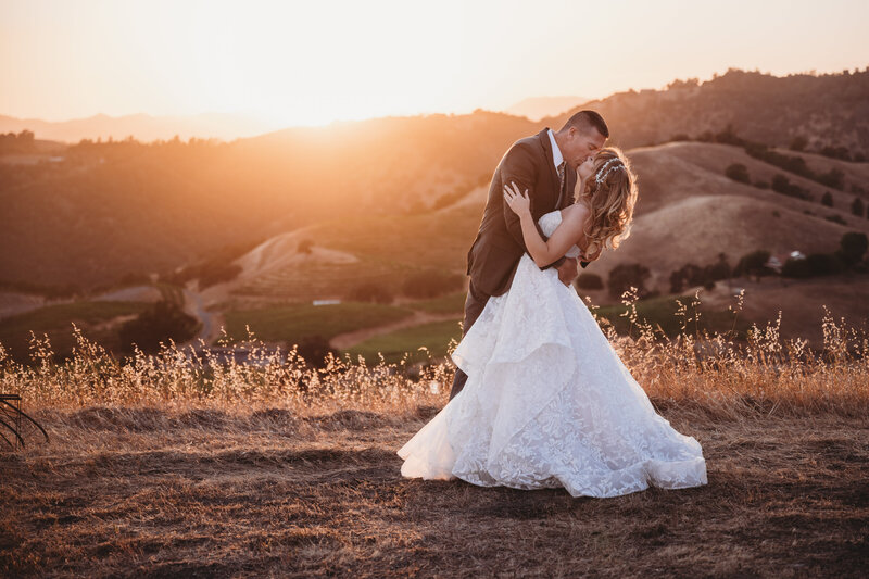 Groom dipping bride in front of a California sunset