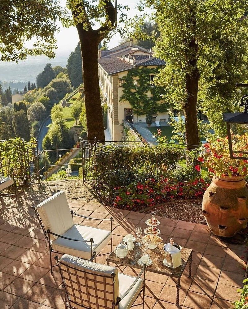 A refined and elegant writing desk at Borgo Santo Pietro with a large glass vase overflowing with white flowers and greenery