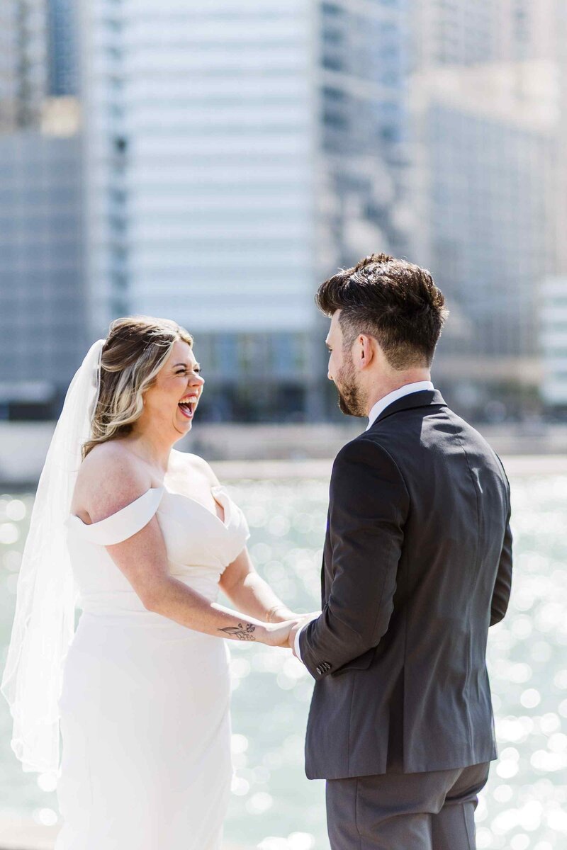Bride laughs while groom says his vows in front of the Chicago skyline