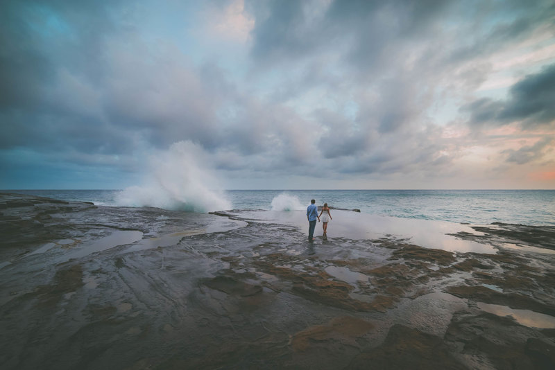 A couple hangs out near the ocean during their Oahu elopement session.