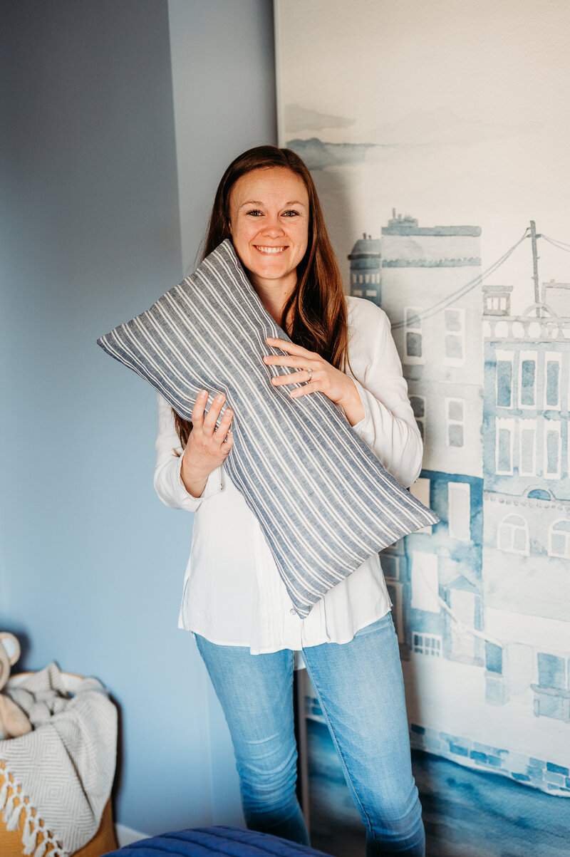 woman holding a decorative pillow and smiling