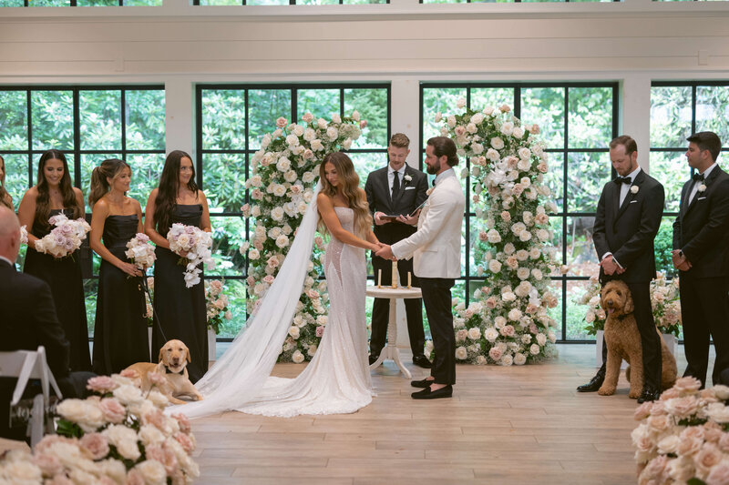 Bride looks back at dog on her veil during wedding ceremony in Highlands, North Carolina. 