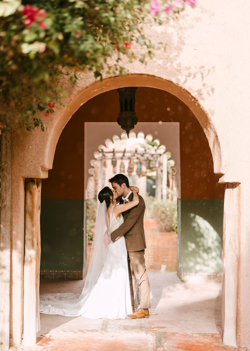 bride and groom smiling while standing against wall