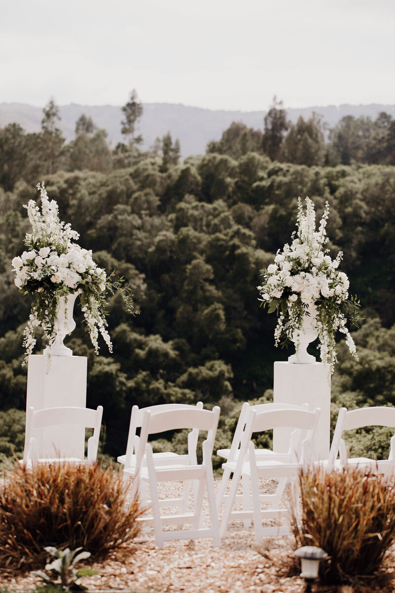 Wedding venue with white chairs  and white flroal decoration on plateu