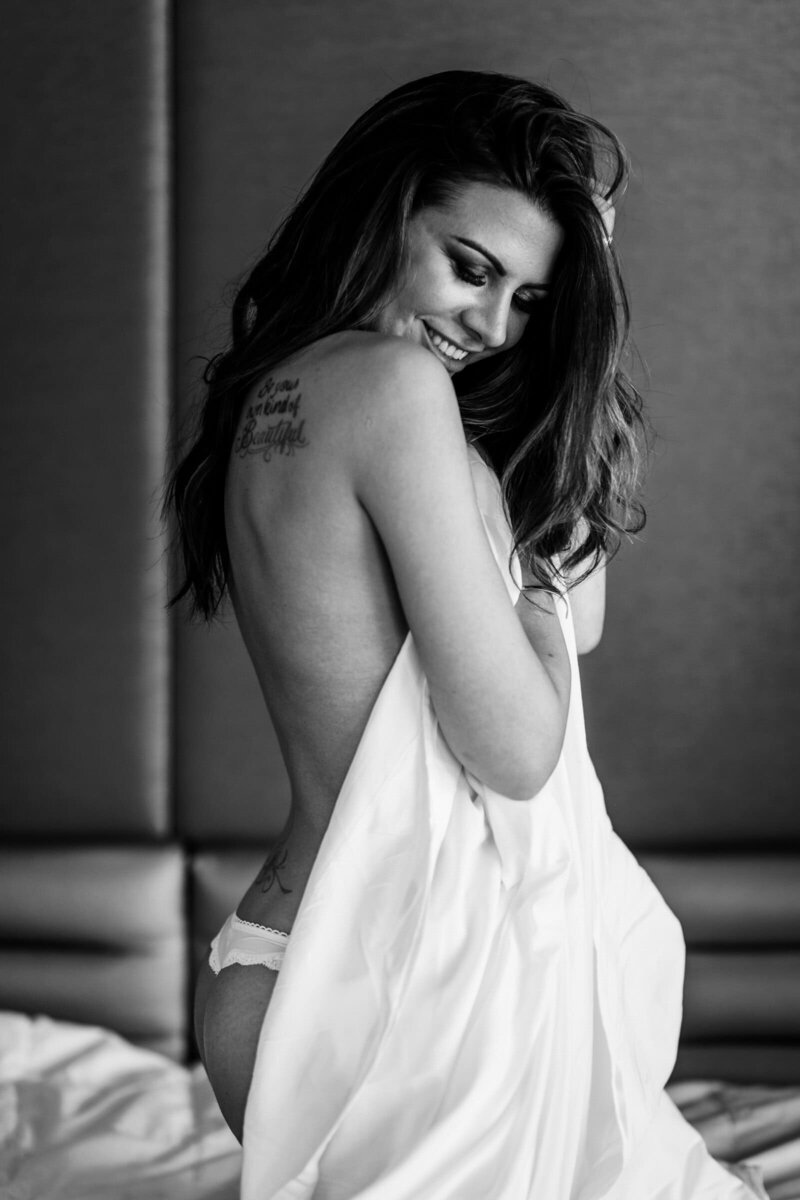 Bridal boudoir photo of bride wrapping herself up in a sheet