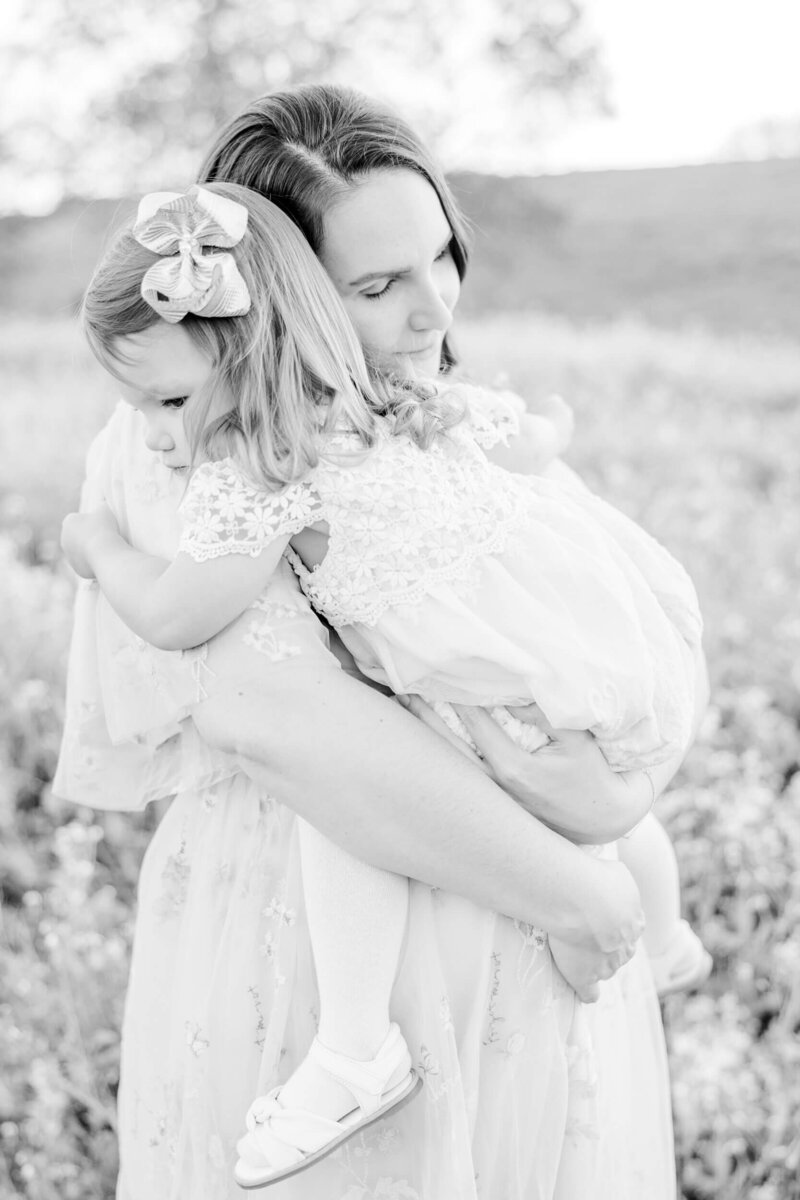 Black and white image of a pregnant mother holding her toddler daughter in her arms