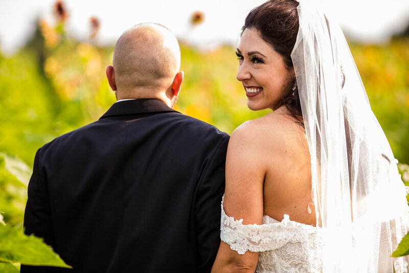 Brie smiles at camera in sunflower field at Port Farms wedding