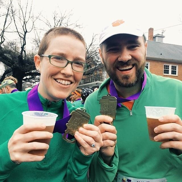 wedding photographers Elyssa and John Kivus pose with running medals and beer after a race in Raleigh, North Carolina