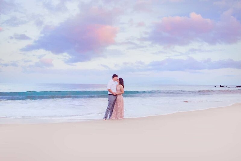 woman wearing a long pastel pink dress leans in to kiss her partner during their Maui couples photoshoot