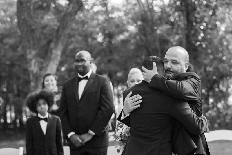 Father of bride hugging groom