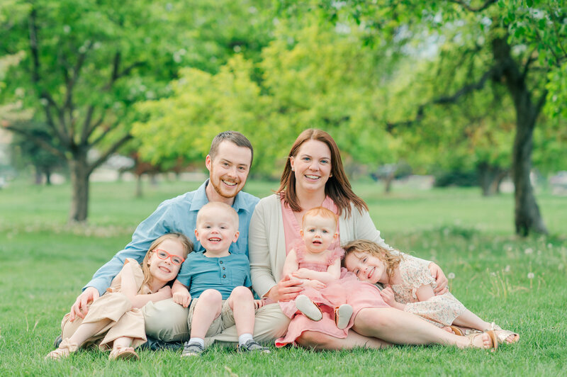 denver wedding photographers posing with her family in an open green field for their denver family photos