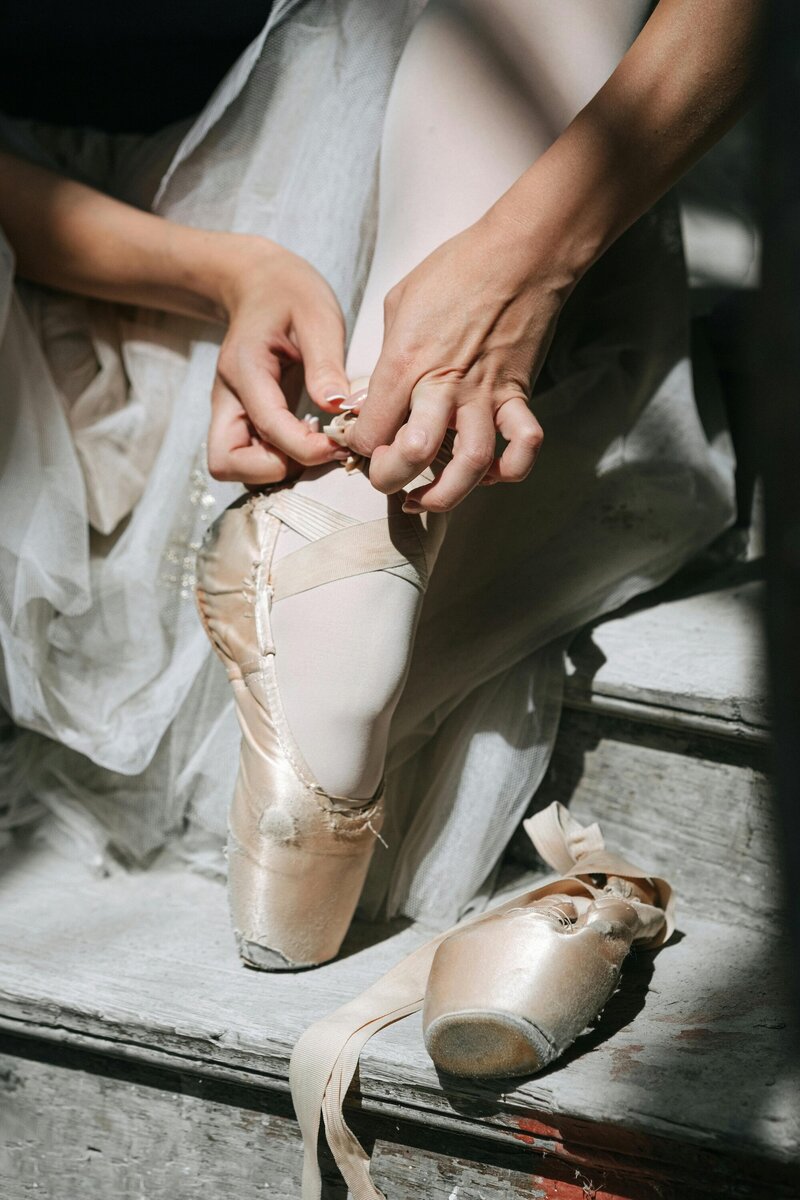 Ballerina tying her pointe shoes, having newfound confidence after artist coaching as a performer