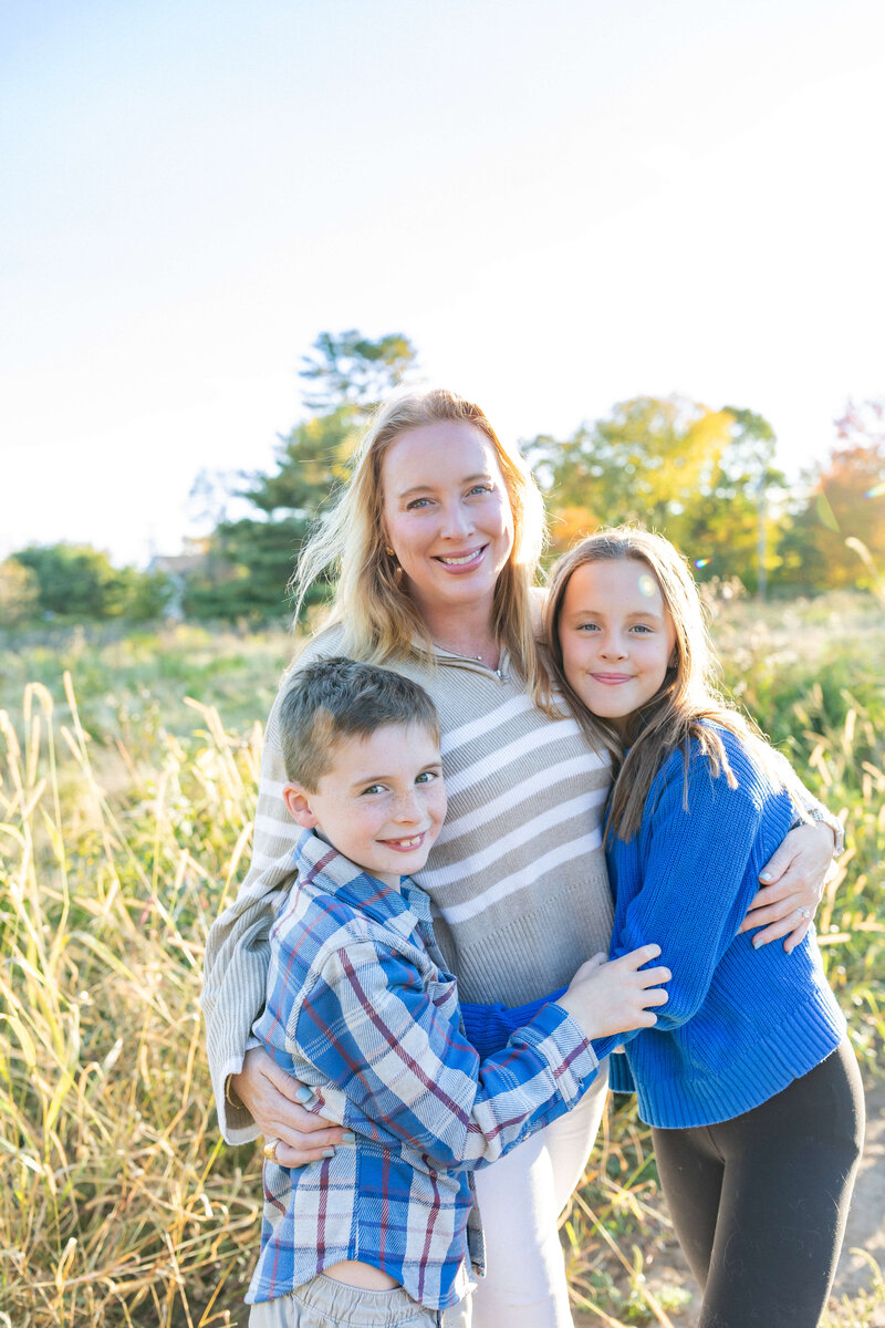 photo of mom with her 2 kids boy and girl smiling at camera and hugging each other