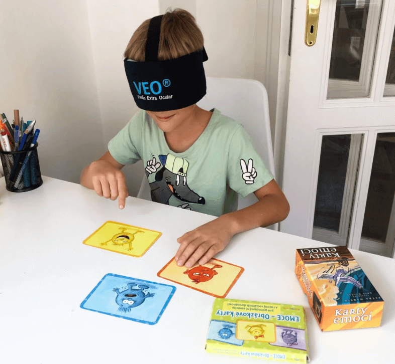 žena se dívá na skleněnou kouli na provázku, kterou drží před sebou, a usmívá se 