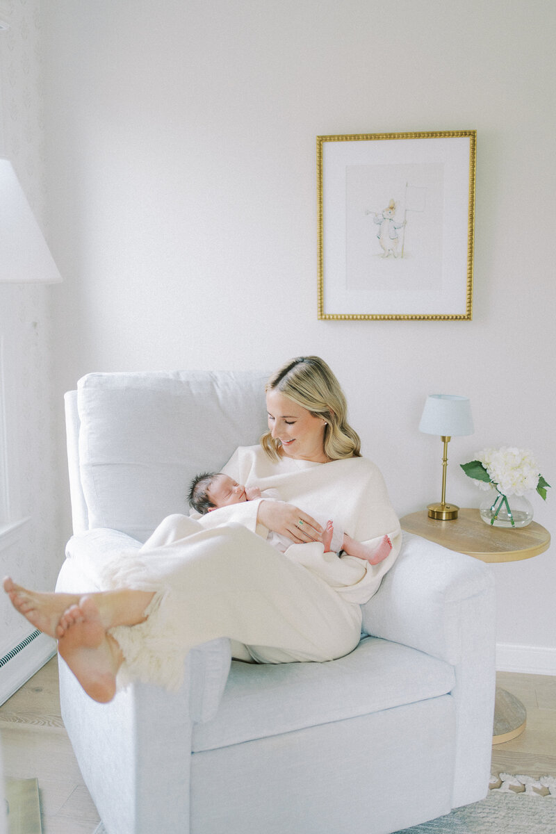 mom laying in chair in nursery holding baby