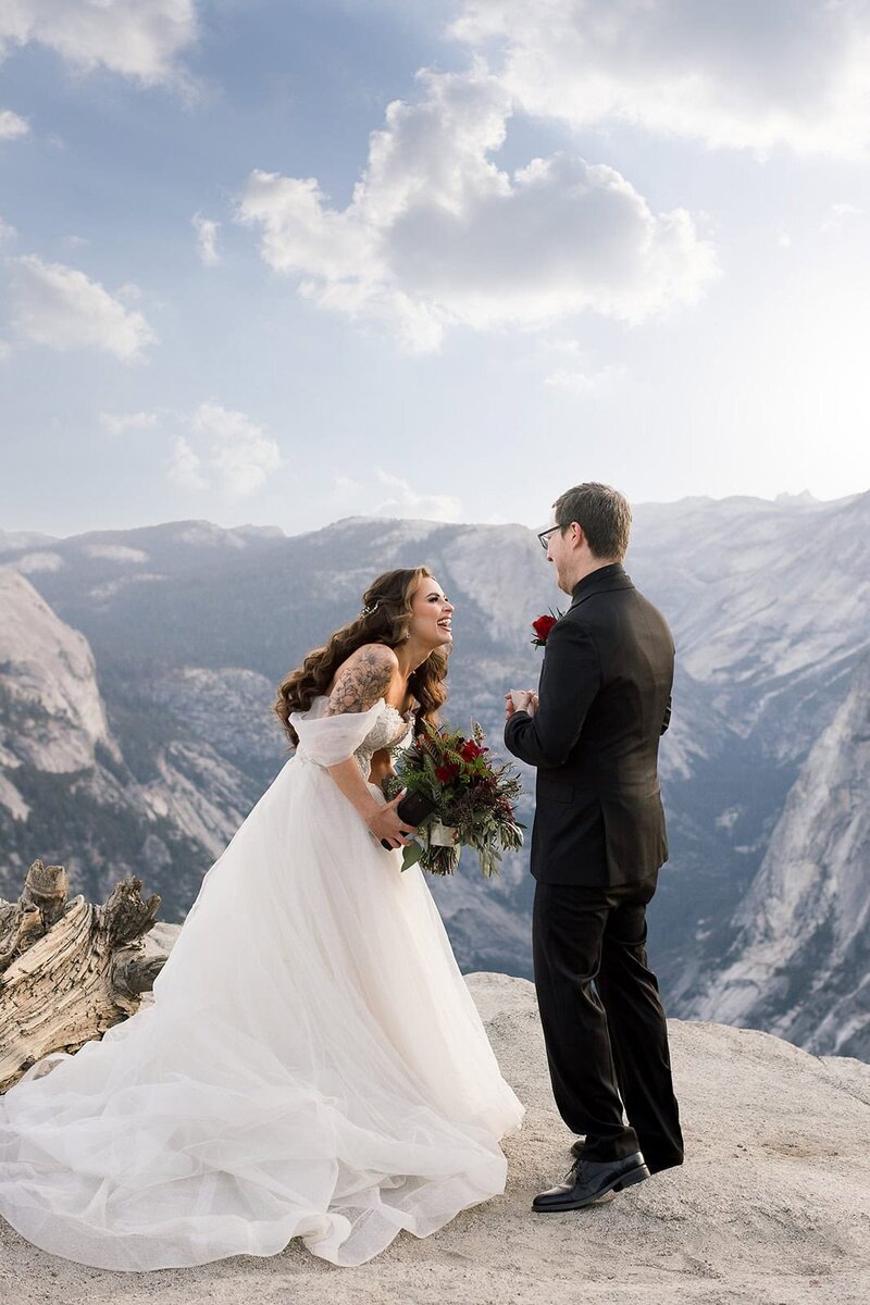 Bride and groom crying during their vows, while standing outside surrounded by pine trees.