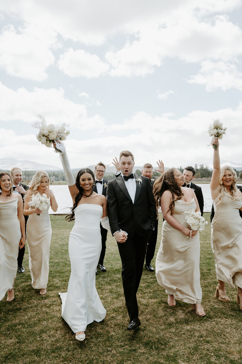 Bride Jenay standing outdoors holding a bouquet of white, mauve, and beige florals including garden roses and ranunculus, by Summer Robbins Flowers in Central Oregon