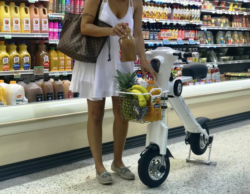 Lady adding groceries to her bike basket on white Go-Bike M1