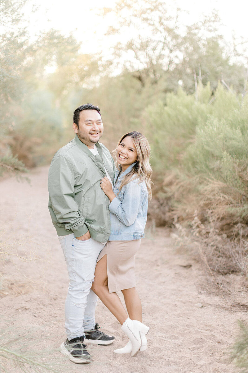 Arizona-based husband and wife photographers stand together, looking into the camera with smiles during a family photoshoot outdoors.
