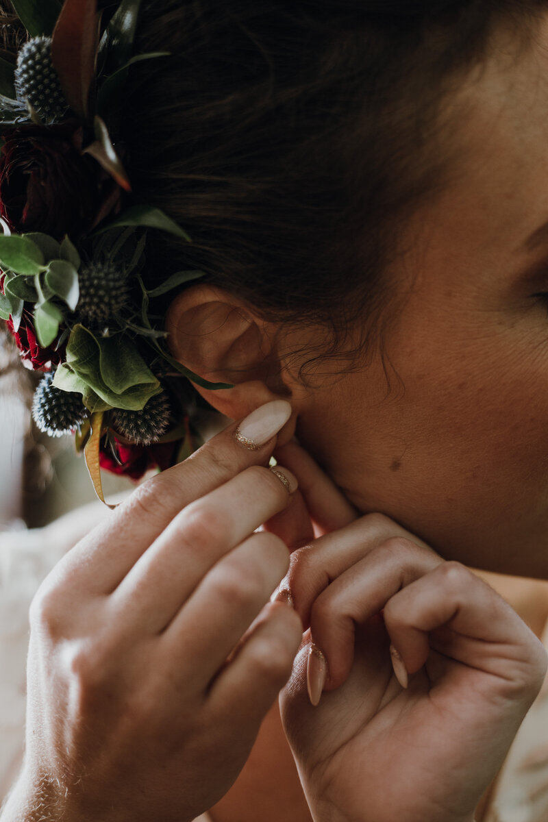 bride putting white earrings in