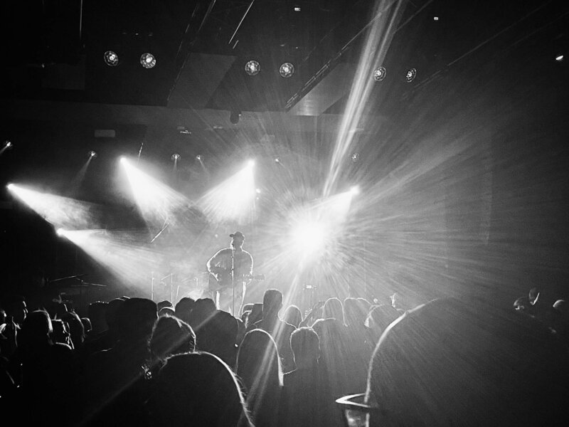 Black and white photo of band concert audience with light flares from stage lights