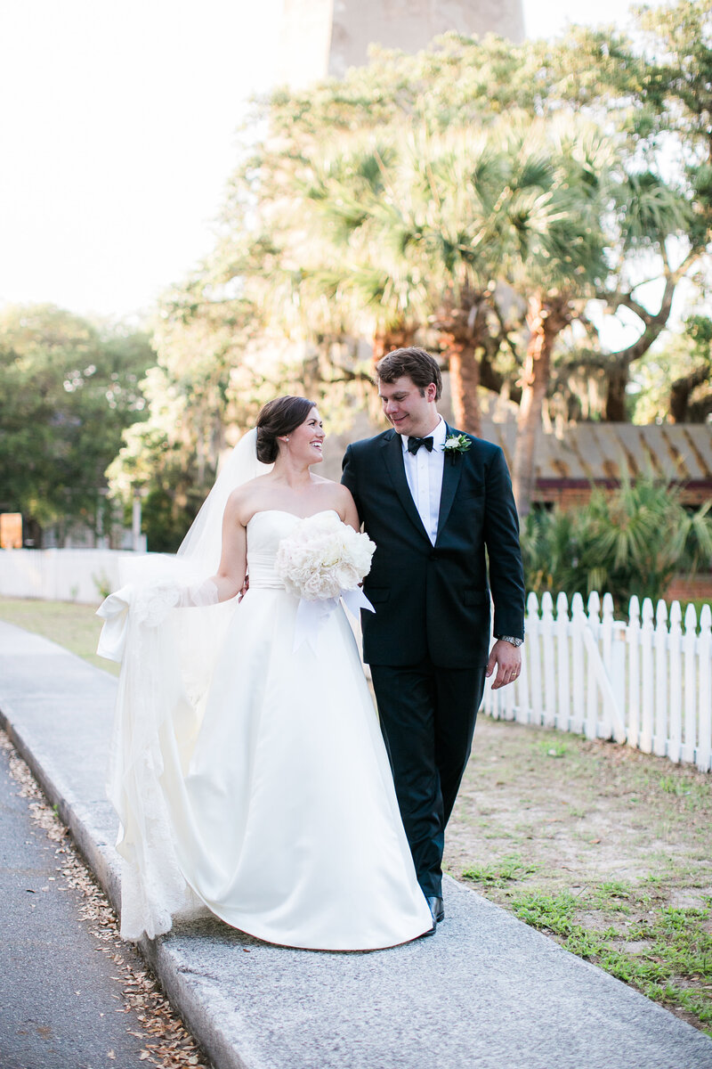 Bald Head Island wedding couple walks past lighthouse  with photographer