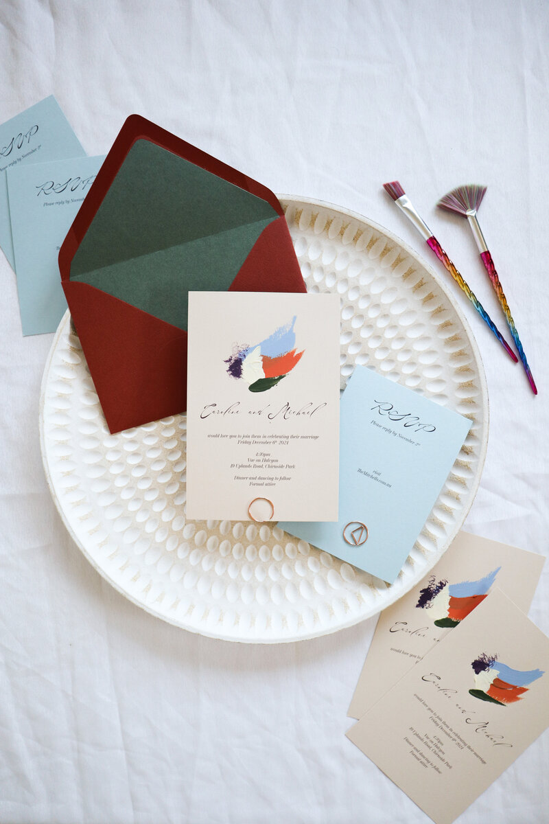 Unique and vibrant wedding invitations in a pink and purple colour palette and bold white text. Invitations paired with a purple and dark yellow envelope,  and matching wedding menu and escort card.