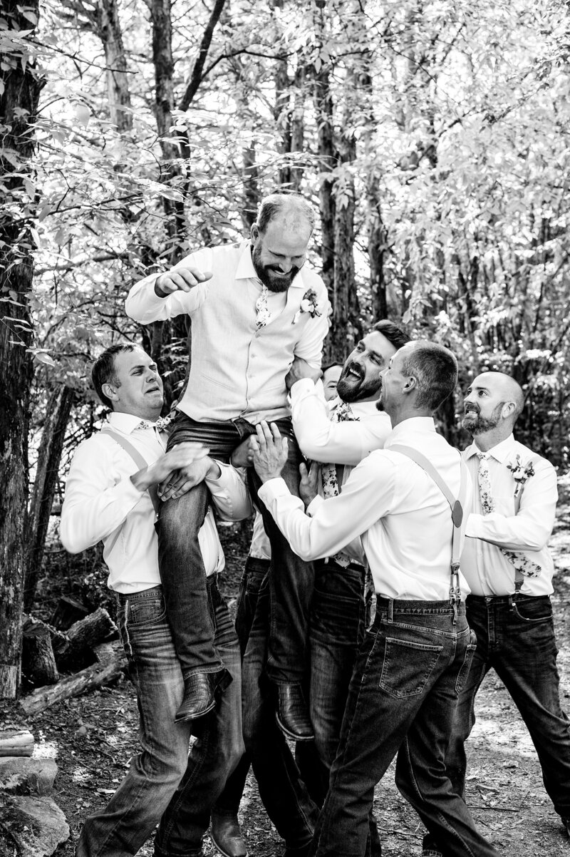 Black and White photo of groomsmen lifting groom into the air