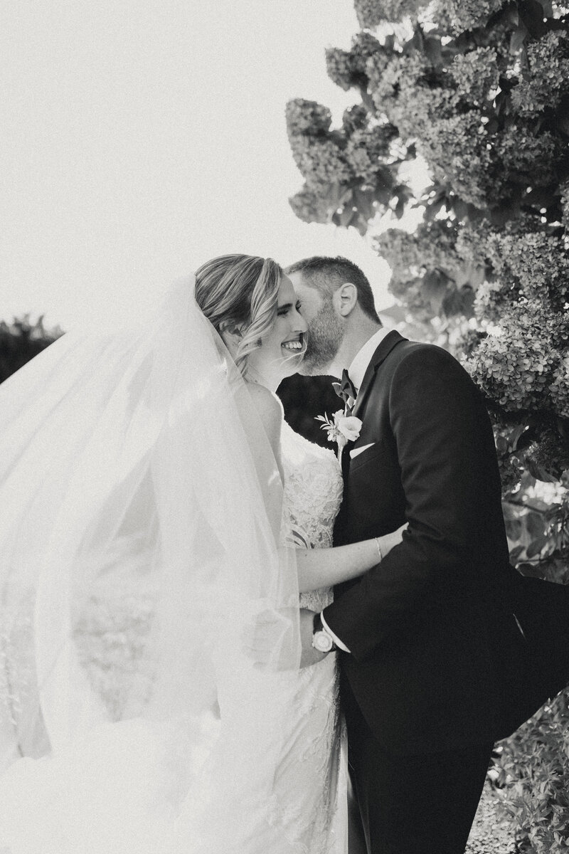 Bride and groom sharing a joyful kiss in black and white during their Portland Maine wedding.