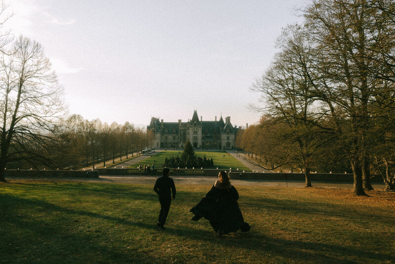 A couple running towards The Biltmore Estate in Asheville NC during sunset in the fall surrounded by the Blue Ridge Parkway, photographed by Andrea-Marie Photography
