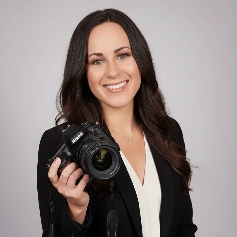 Denver boudoir and wedding photographer smiling with Nikon camera – female photographer with tattoos and blonde hair sitting on a velvet couch, ready to capture intimate, candid moments with confidence and creativity.