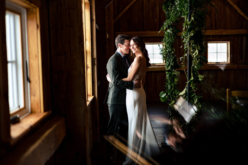 A wedding couple embracing in the barn during their winter wedding at Zingermans Cornman Farms in Dexter Michigan