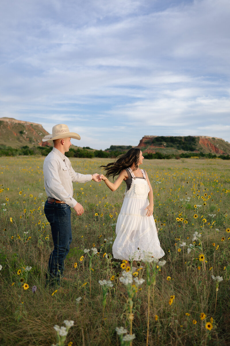 couple spinning around the field during their okc engagement photos