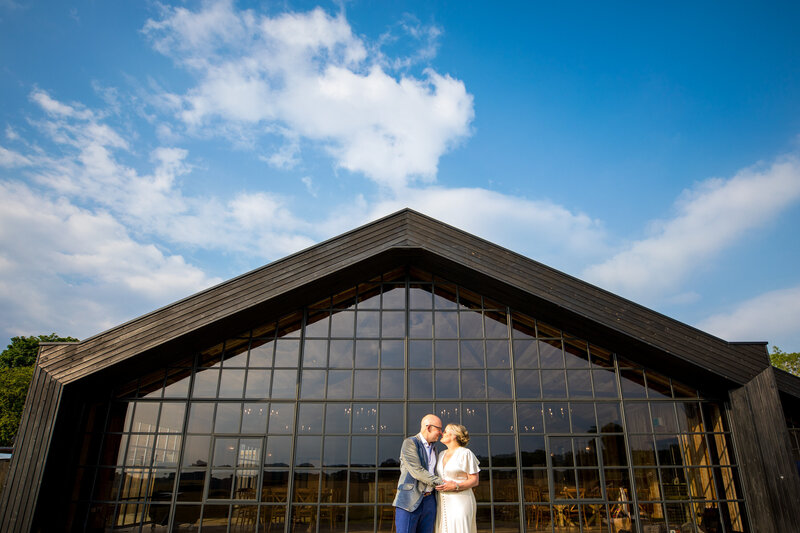 Couple in front of glass church for wedding portrait