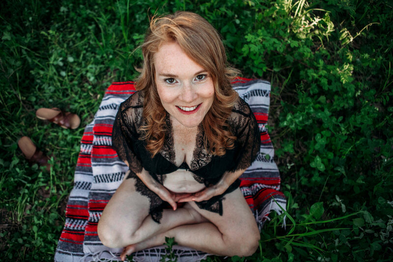 expecting mom sits cross legged on blanket in grass