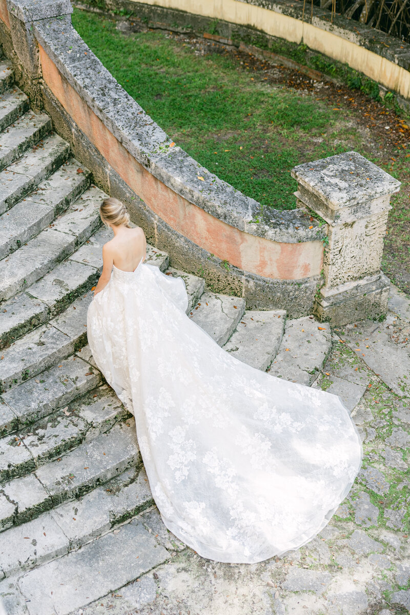 A stunning bride gracefully walks down the historic stone staircase at Vizcaya Museum & Gardens in Miami. Capturing timeless elegance and luxury wedding photography at one of Florida's most iconic wedding venues. Wedding photographer