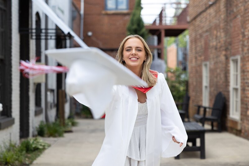 senior girl throwing cap in graduation gown